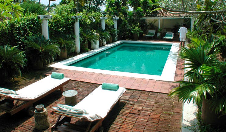 The Sun House Sri Lanka outdoor pool loungers surrounded by greenery