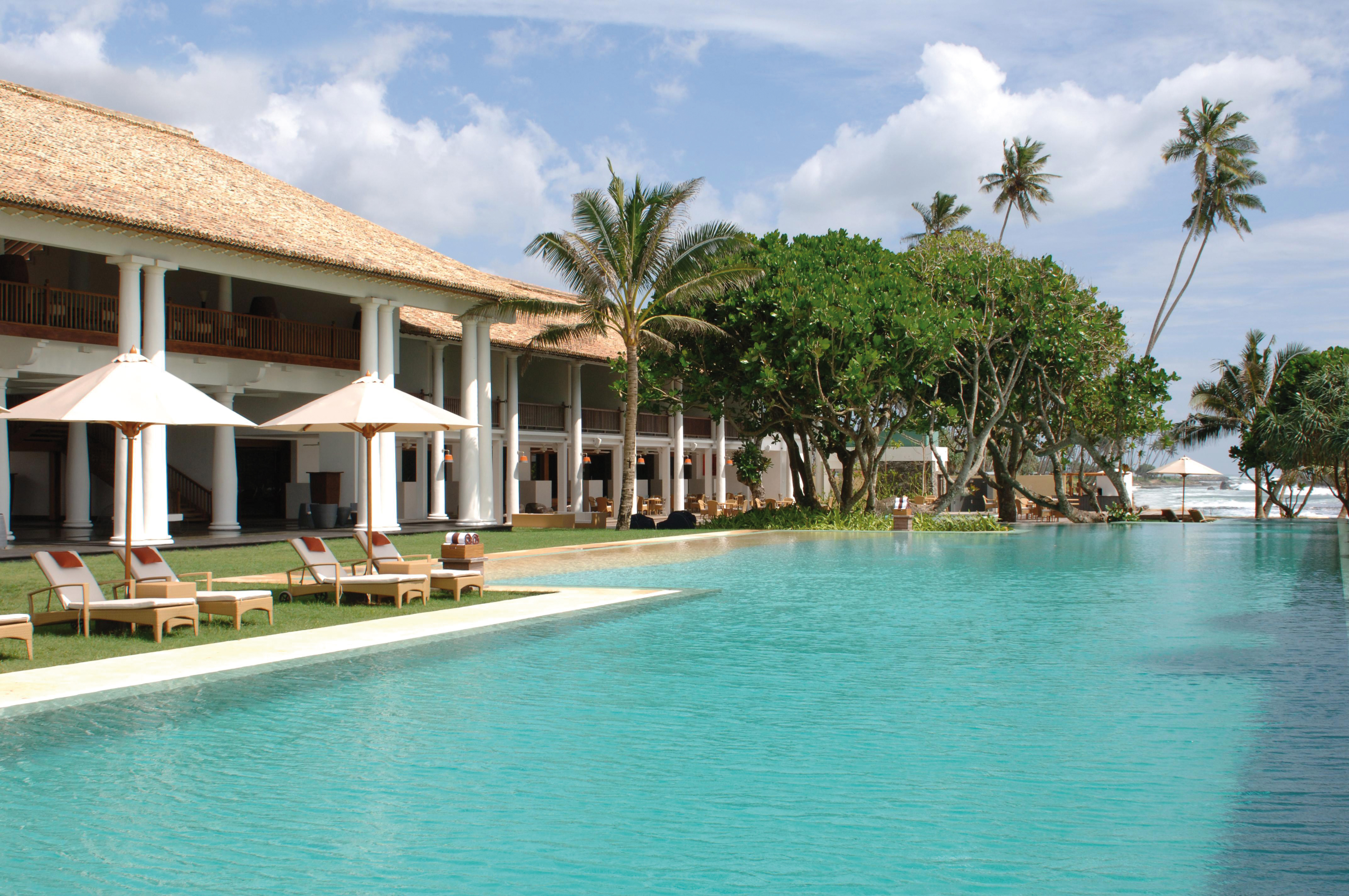 Outdoor swimming pool with palm trees and sun loungers