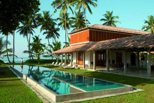 Swimming pool with beach hut in the background and palm trees