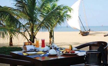 Jetwing Beach Sri Lanka beach dining table set for breakfast for two beach boat and sea in background