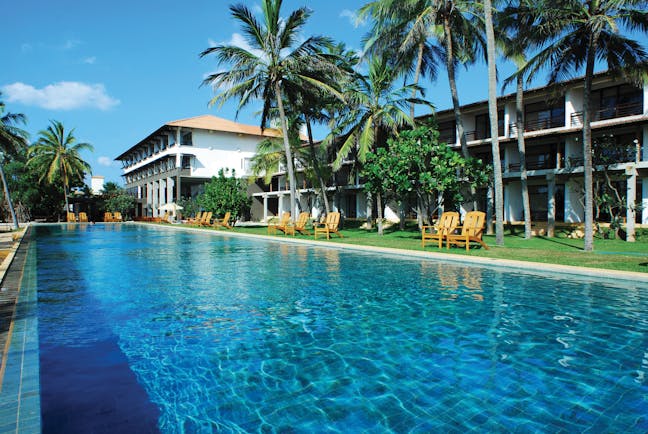 Pool and hotel exterior with palm trees and white building in distance