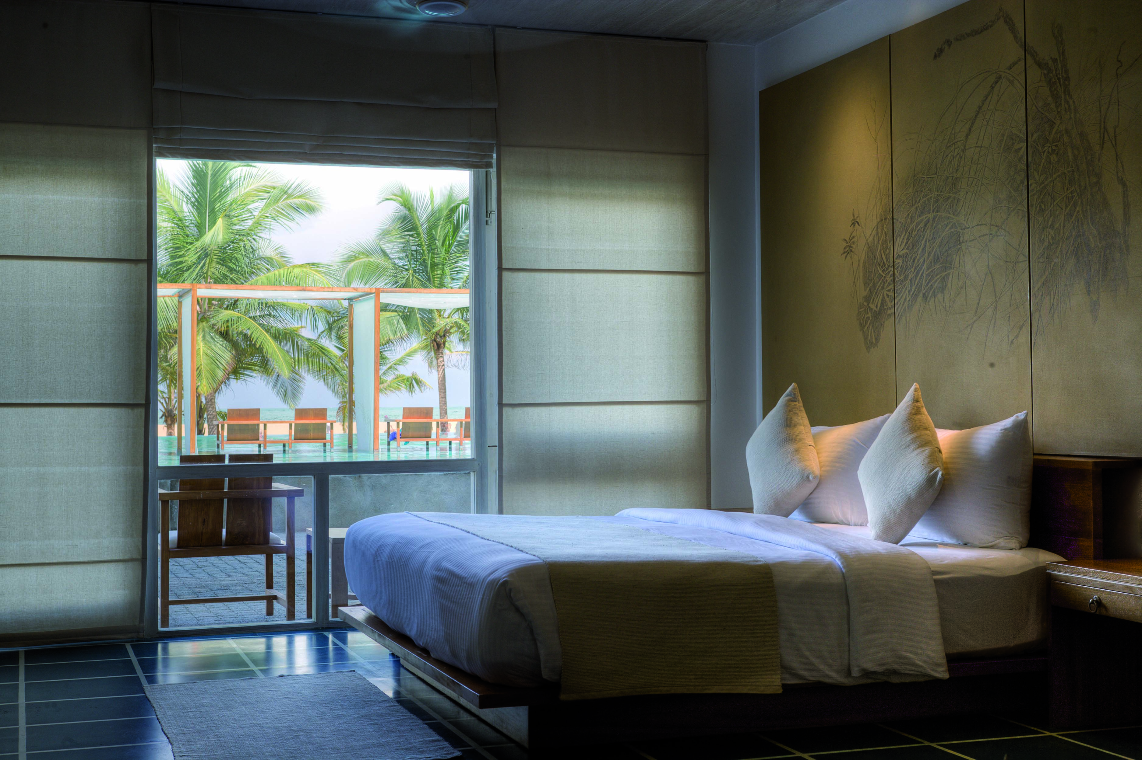 Jetwing Blue Sri Lanka deluxe room bed window overlooking pool modern décor