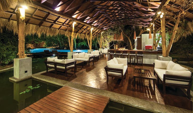 Jungle Beach bar, thatched structure beside pool with sofas and tables, soft lighting