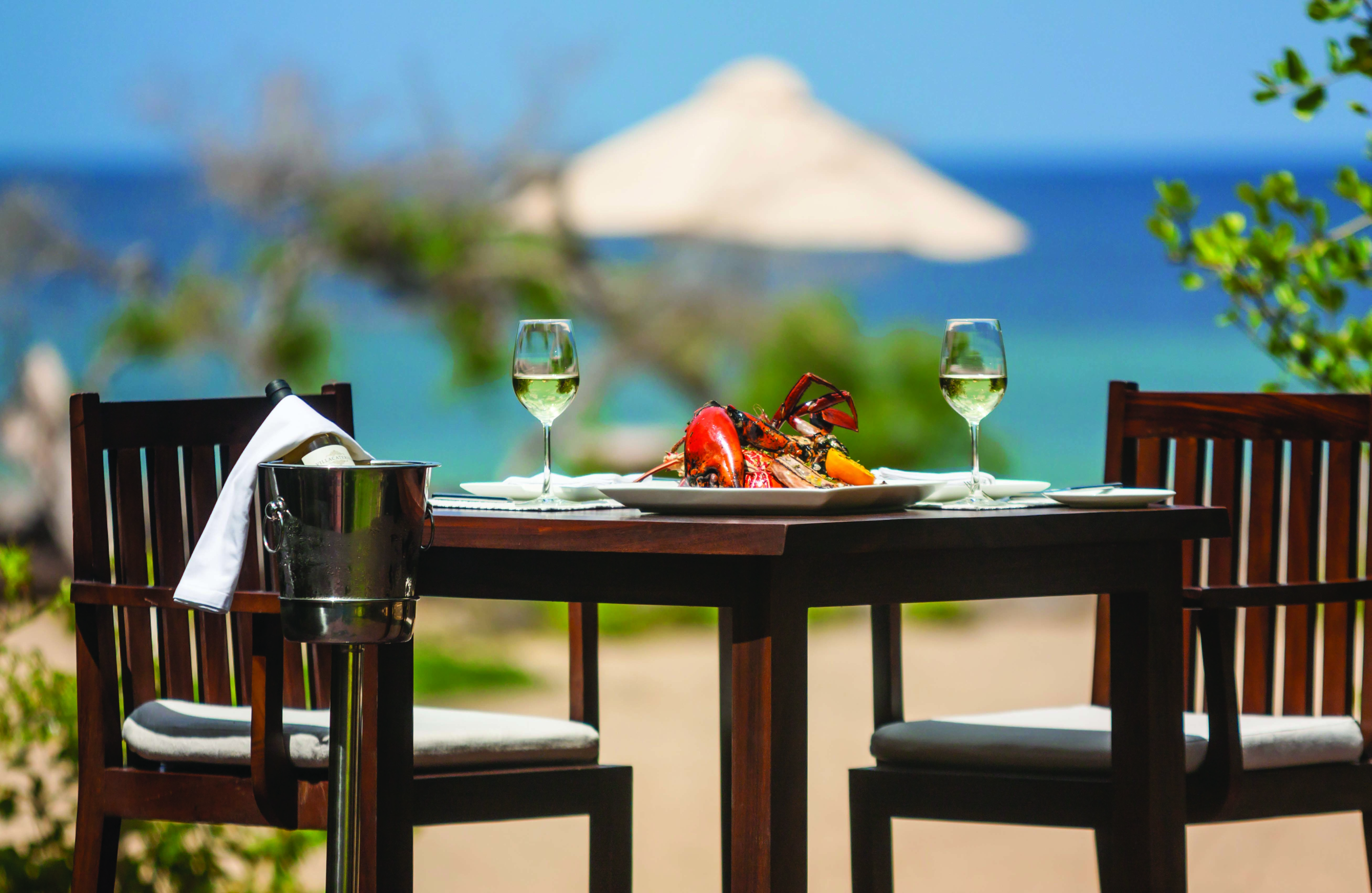 Jungle Beach beach dining, table set with seafood and wine on sand near to beach