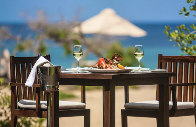 Jungle Beach beach dining, table set with seafood and wine on sand near to beach