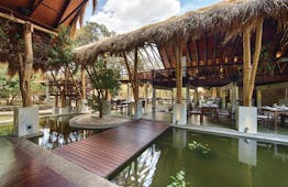 Jungle Beach open air resturant with thatched covering, placed beside pond, tables and chairs