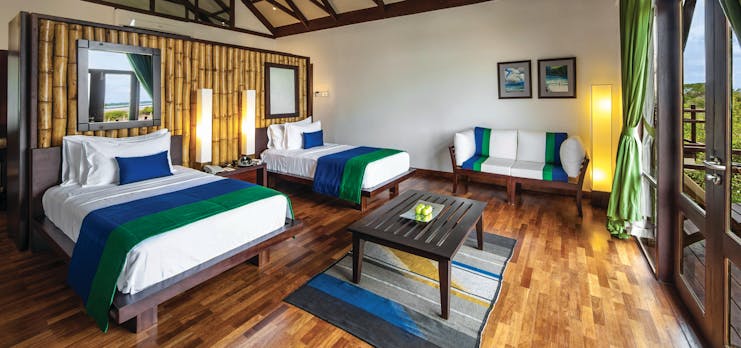 Jungle Beach twin room, two beds, sofa, wooden floor, balcony access, bright modern decor