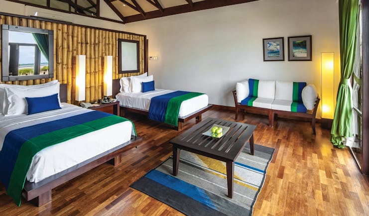 Jungle Beach twin room, two beds, sofa, wooden floor, balcony access, bright modern decor