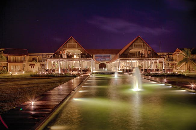 Exterior of hotel at night with fountains in front 