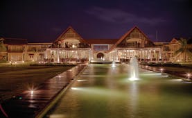 Exterior of hotel at night with fountains in front 