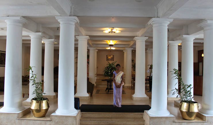Hotel Suisse Sri Lanka lobby with white columns and member of staff