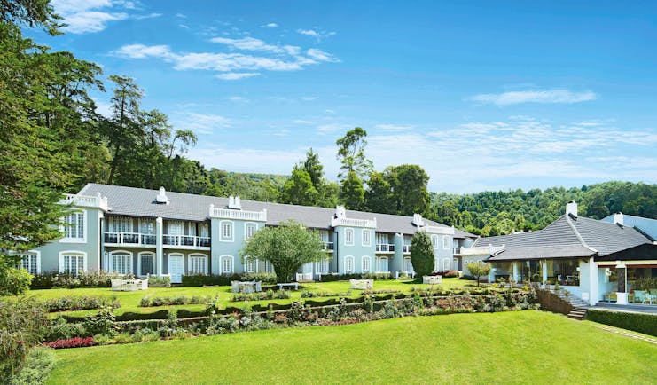 Panoramic exterior view of whole hotel, a blue building near grass