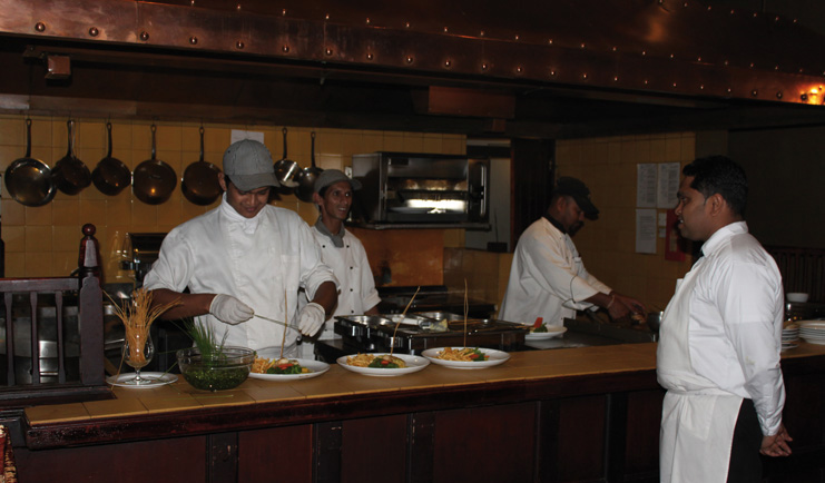 Restaurant with yellow ceiling and green chairs with dining tables set out 