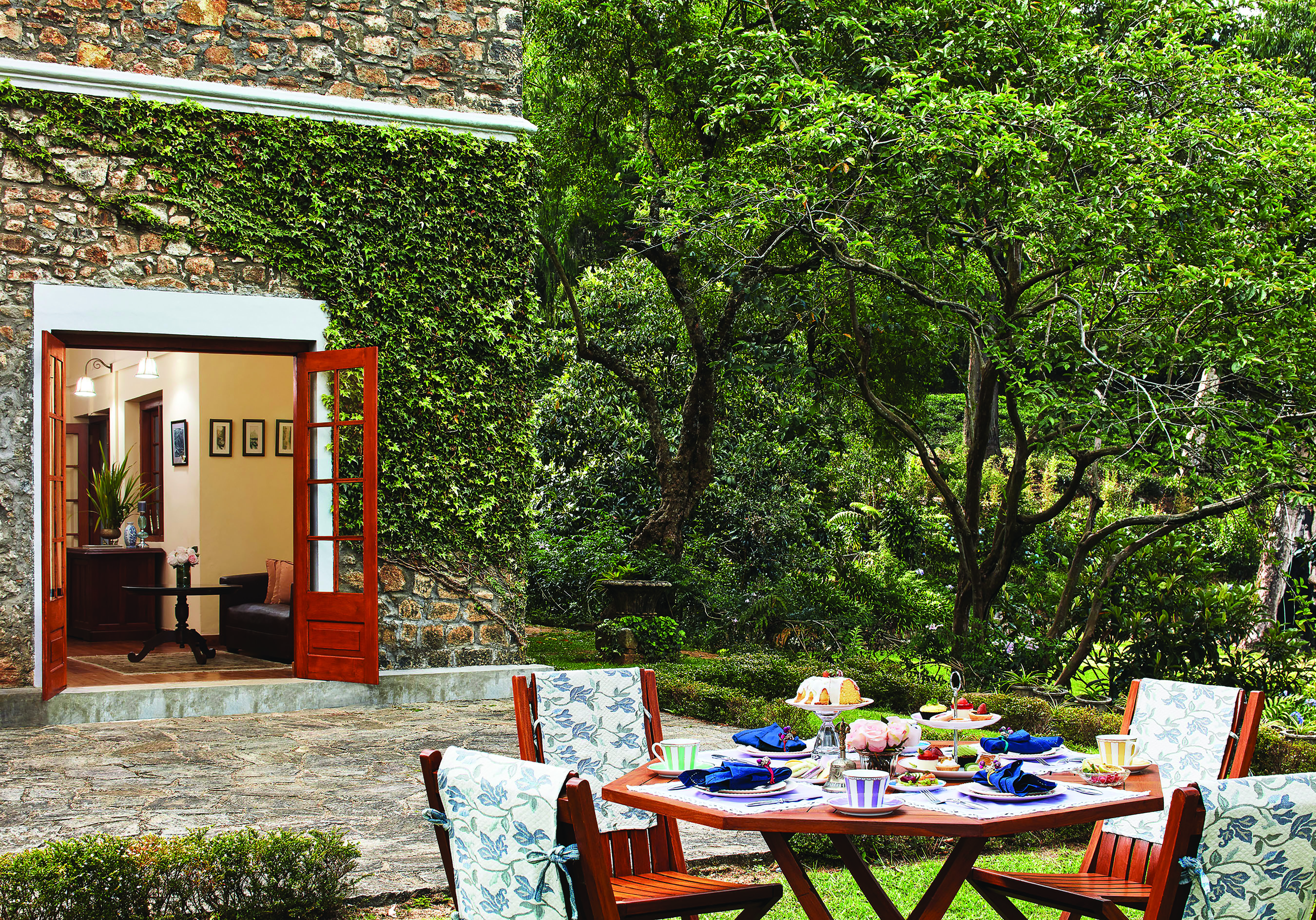 Jetwing Warwick Gardens dining terrace, table set on lawn, trees 