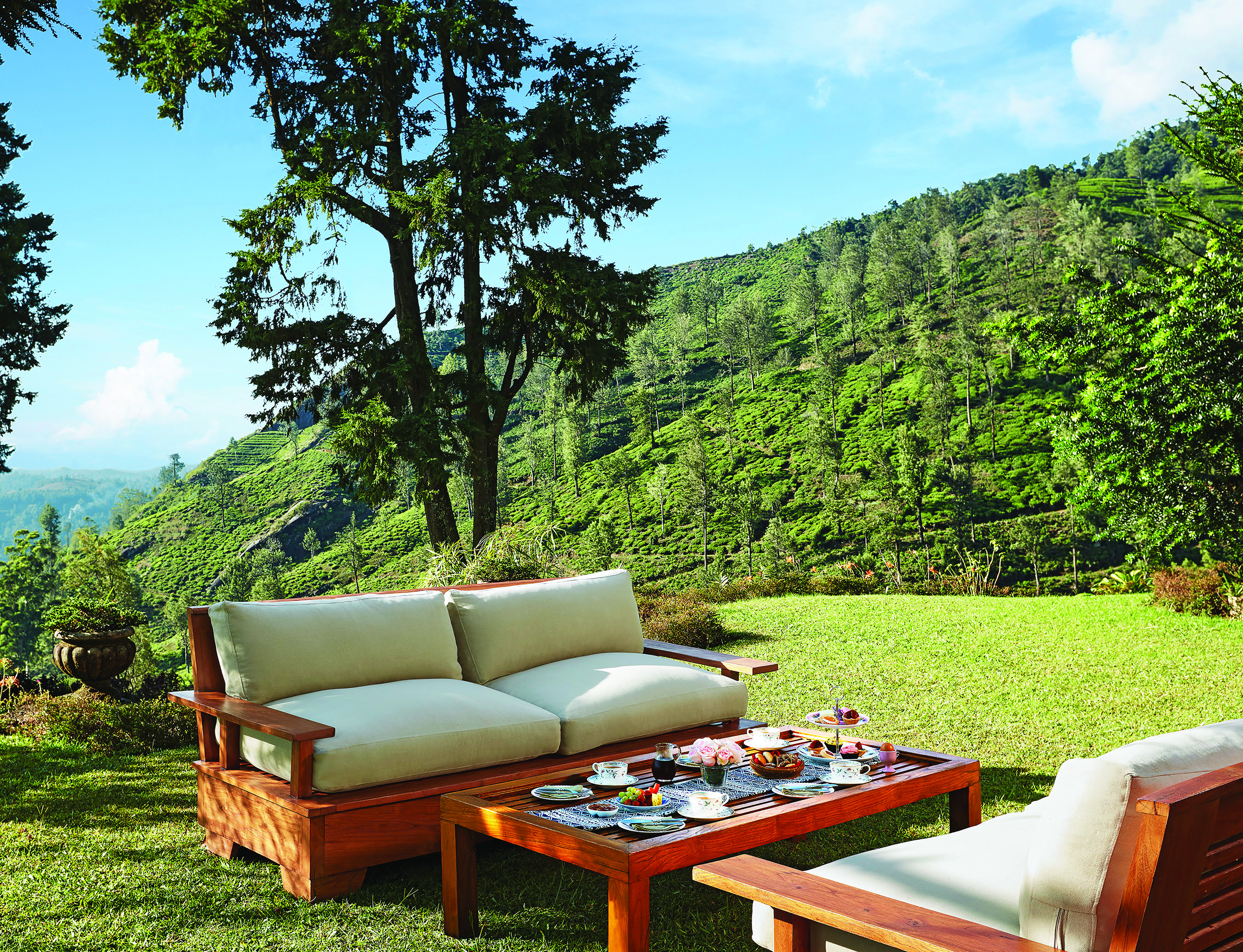 Jetwing Warwick Gardens table set for breakfast in the grounds, outdoor sofas, hills in background