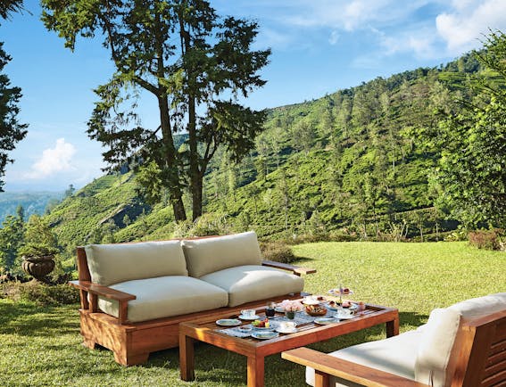 Jetwing Warwick Gardens table set for breakfast in the grounds, outdoor sofas, hills in background