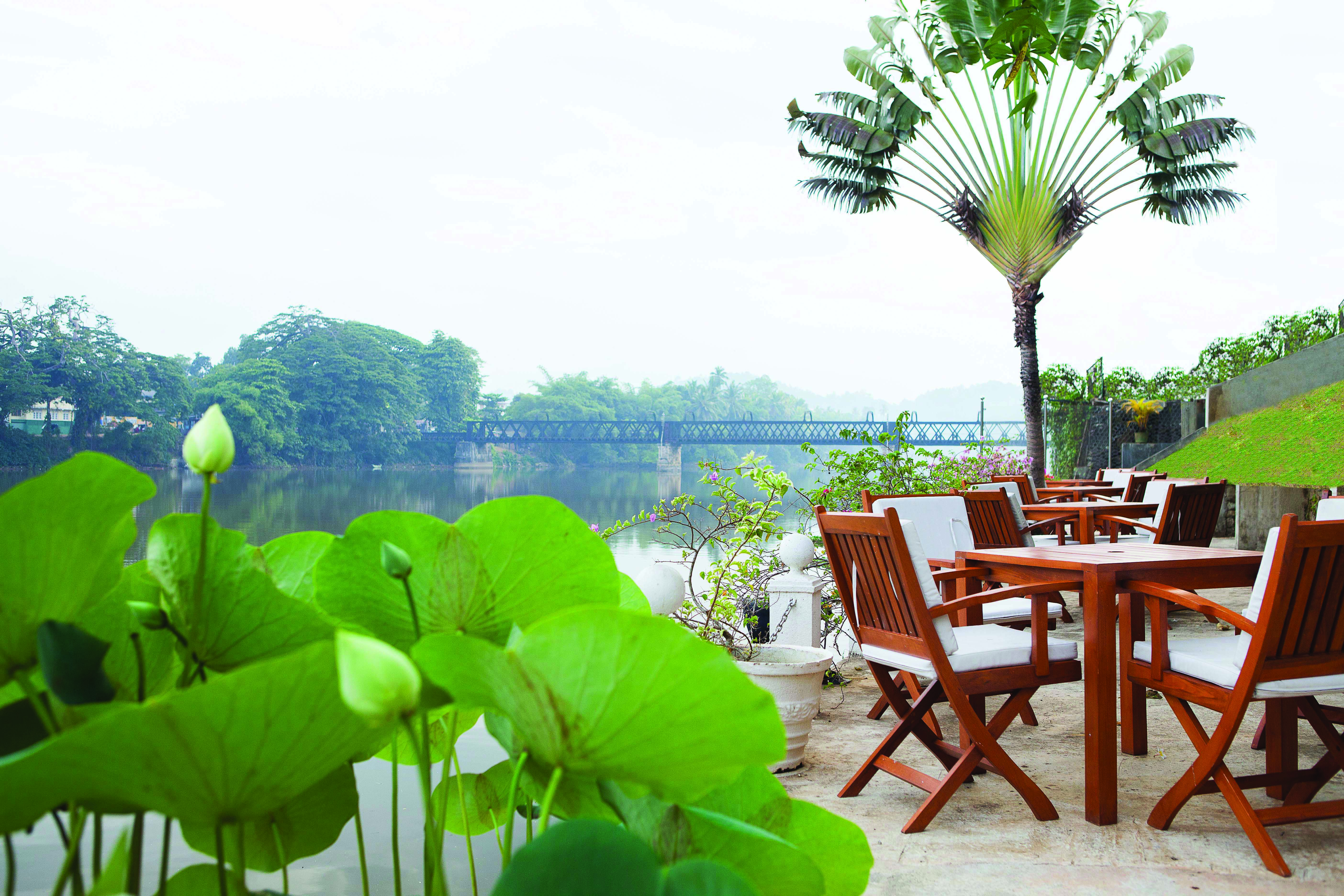 Mahaweli Reach Hotel riverside terrace, tables and chairs overlooking river