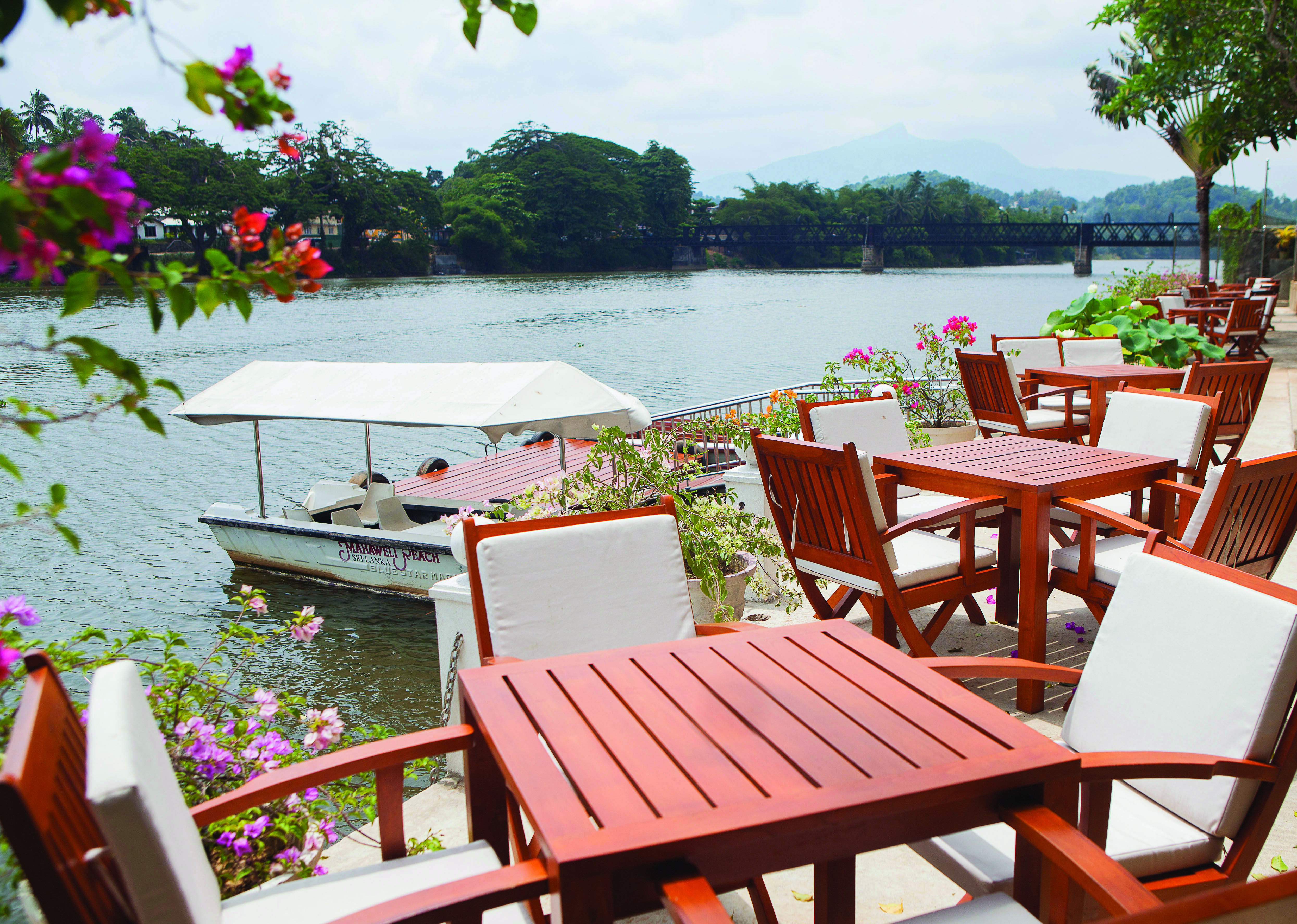 Mahaweli Reach Hotel terrace, tables and chairs overlooking river