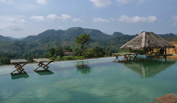Rainforest Edge infinity pool overlooking mountains, cabana and chairs in the water