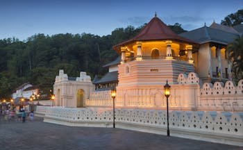 Exterior evening shot of the Temple of the Sacred Tooth Relic, white buildings lit up by lanterns