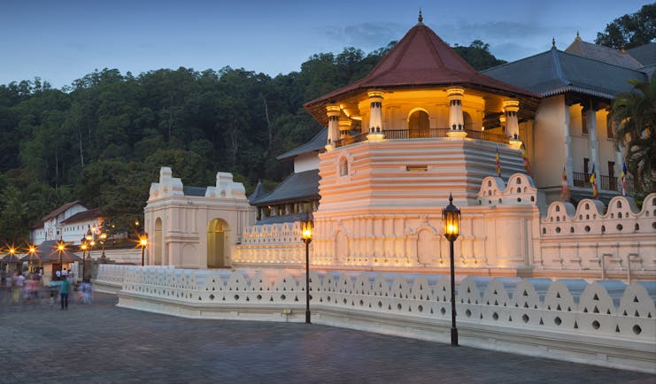 Exterior evening shot of the Temple of the Sacred Tooth Relic, white buildings lit up by lanterns