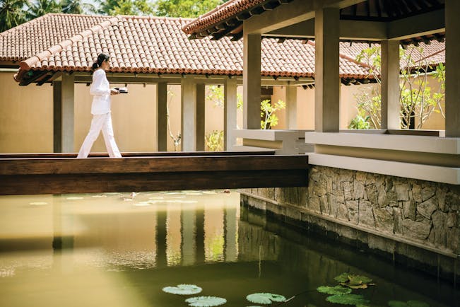 Anantara Kalutara Sri Lanka spa exterior buildings walkway over water female spa worker