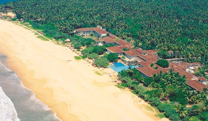 Aerial view of hotel and beach with greenery surrounding it and a beach nearby