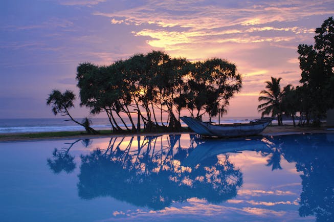 Heritance Ahungalla Sri Lanka poolside outdoor pool with traditional wooden boat at sunset