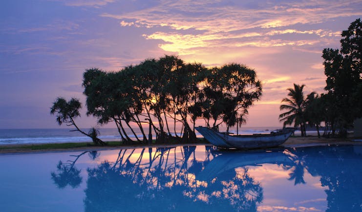 Heritance Ahungalla Sri Lanka poolside outdoor pool with traditional wooden boat at sunset