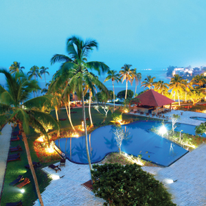 Hikka Tranz gardens with pool, lawn, palm trees and sea in the background