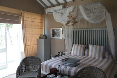 Bedroom with double bed, drapes and arm chairs