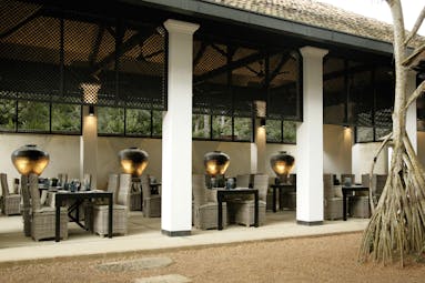 Outdoor dining terrace beneath a veranda with tables and chairs set up for dining 