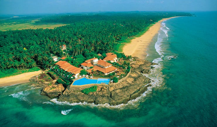 Aerial view of coast and hotel shown on the edge of cliff