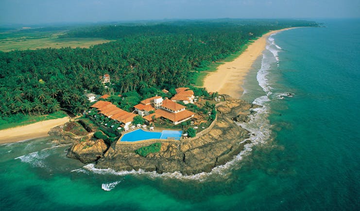 Aerial view of coast and hotel shown on the edge of cliff