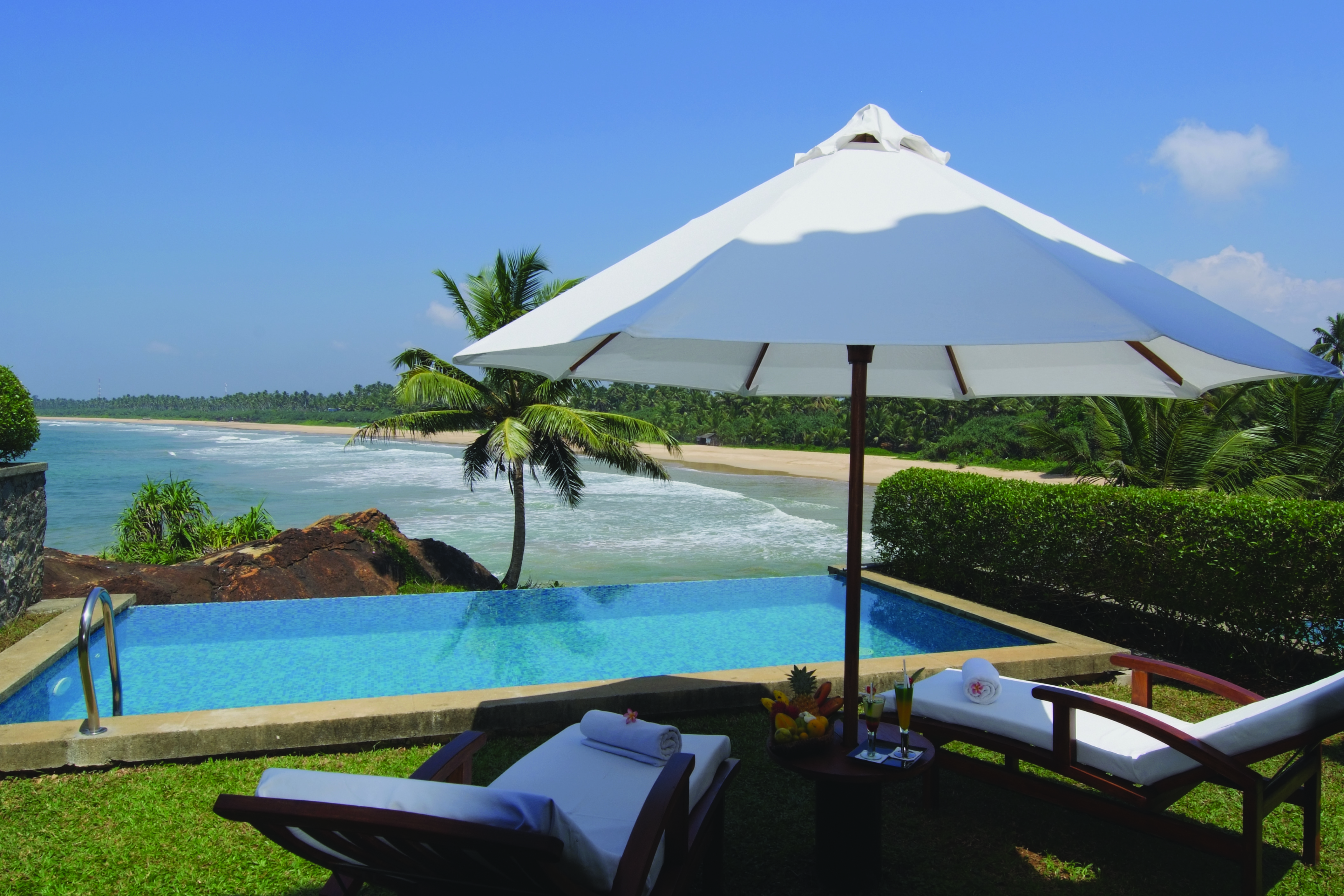 Deluxe suite room with private pool looking over ocean with palm trees nearby 
