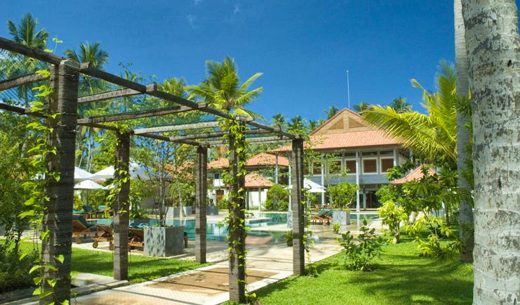 Serene Pavilions Sri Lanka gardens sun loungers palm trees hotel in background