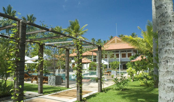 Serene Pavilions Sri Lanka gardens sun loungers palm trees hotel in background