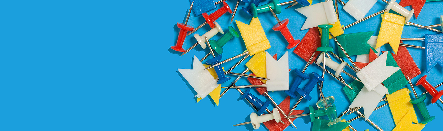Coloured pin flags in white, yellow, red and green on blue surface