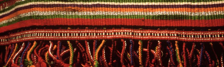 Woven mat in colours of ochre, red, orange and some green stripes