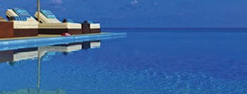 Deep blue infinity pool with sun loungers at Velassaru Maldives